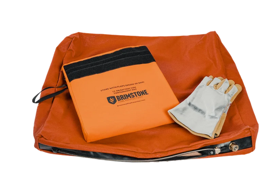 An orange Brimstone fire starter kit containing an orange fabric pouch, a folded orange paper insert with black trim and the Brimstone logo, and a white reflective fire glove, shown on a white background.